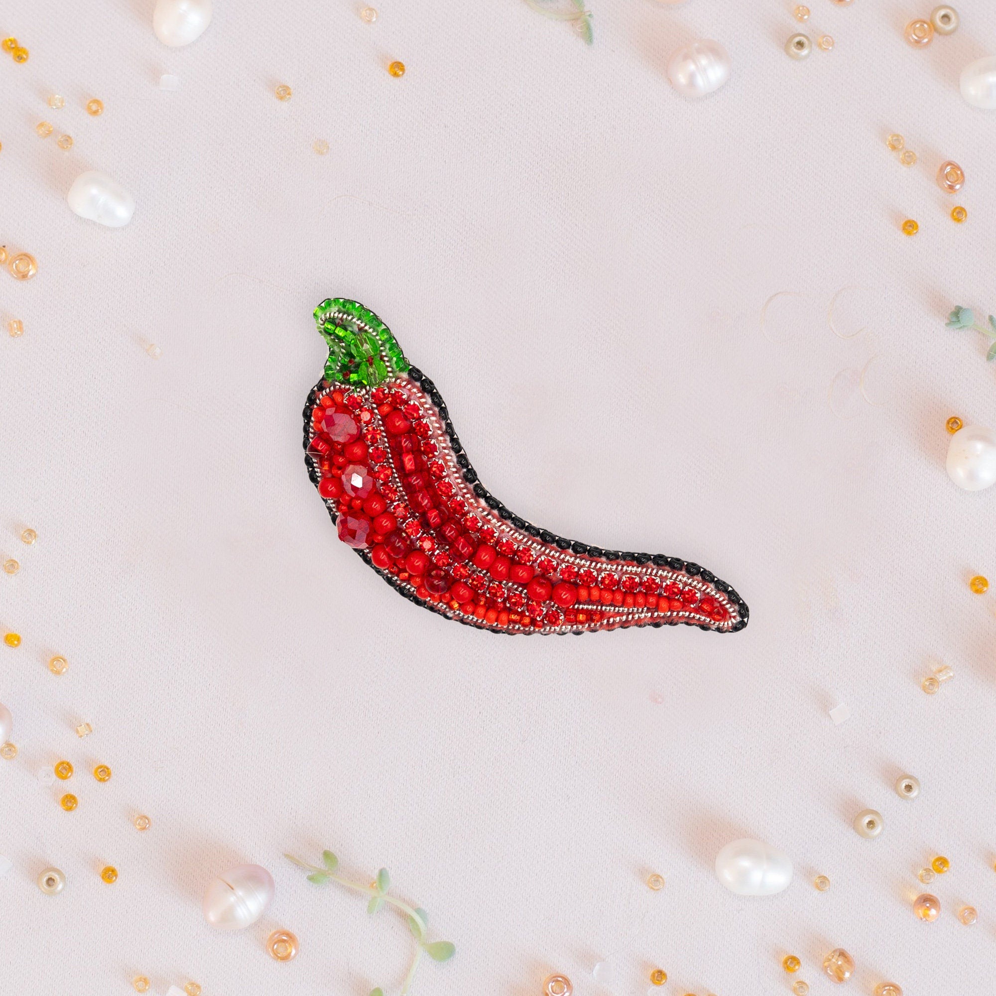 a brooch with a red chili on it